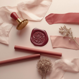 Flat lay of a red wax seal, stamp, and wax sticks.